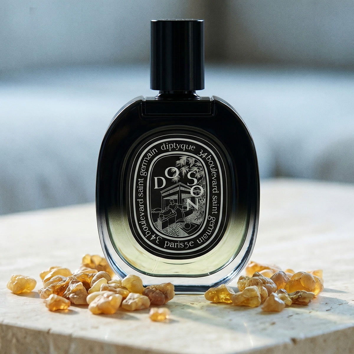 Diptyque Doson EDP on polished limestone with benzoin resin pebbles arranged loosely