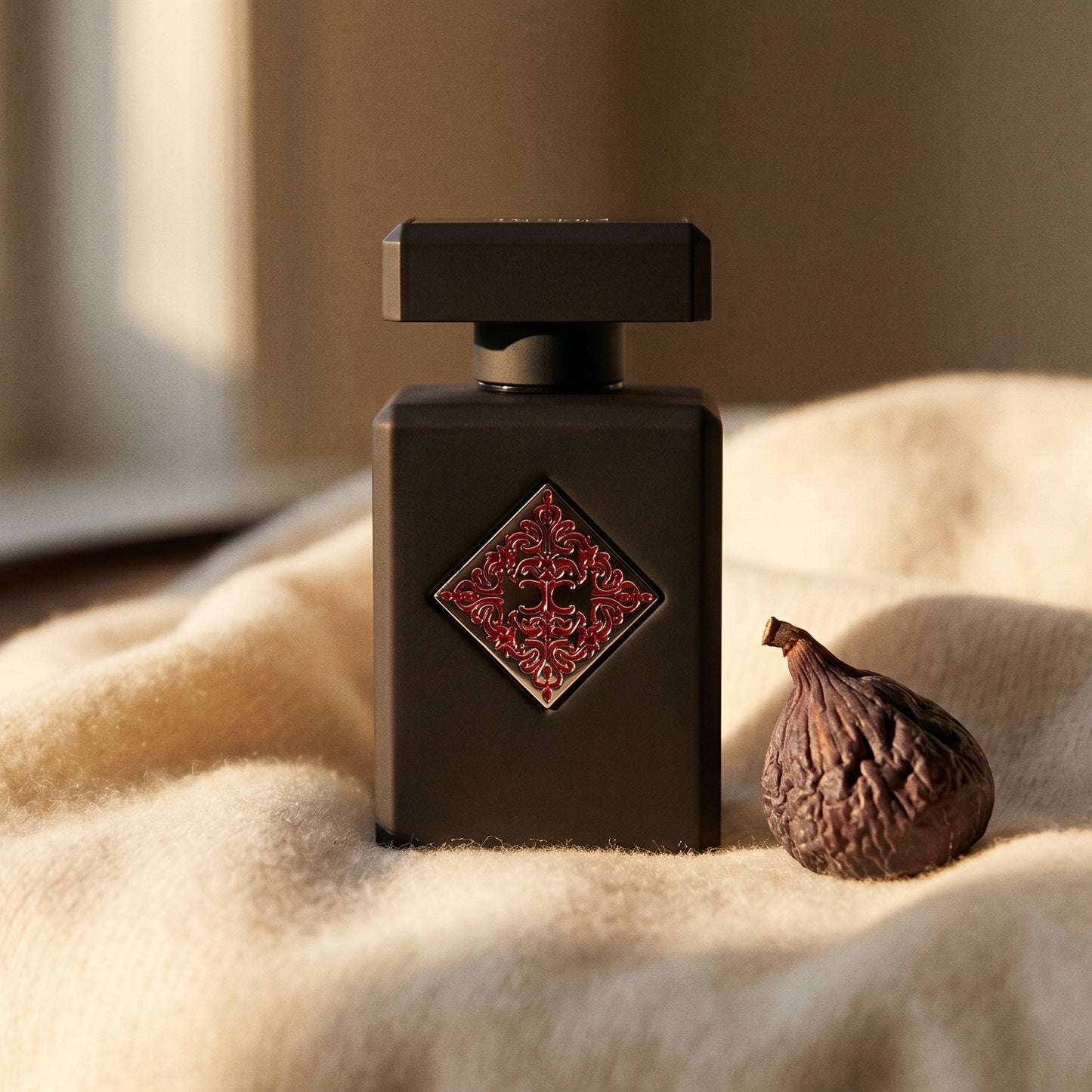 Initio Addictive Vibration EDP on cream cashmere with a single dried fig beside the bottle