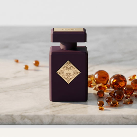Initio Atomic Rose EDP on pale grey marble with amber resin beads scattered to one side