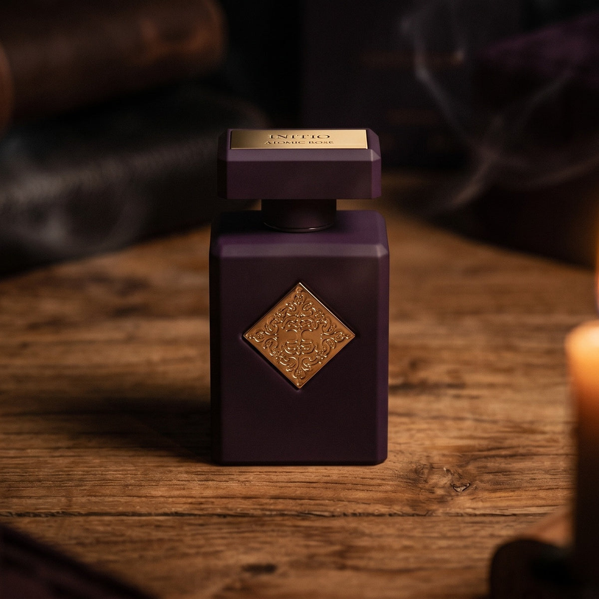 Initio Atomic Rose EDP on aged teak with a candle burning gently to frame-right
