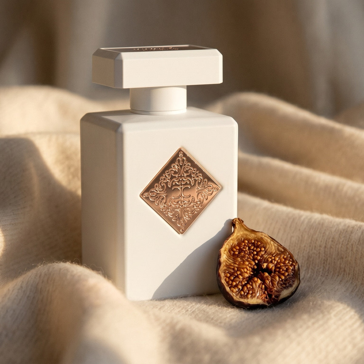 Initio Lift Me Up Extrait de Parfum on cream cashmere with a single dried fig beside the bottle