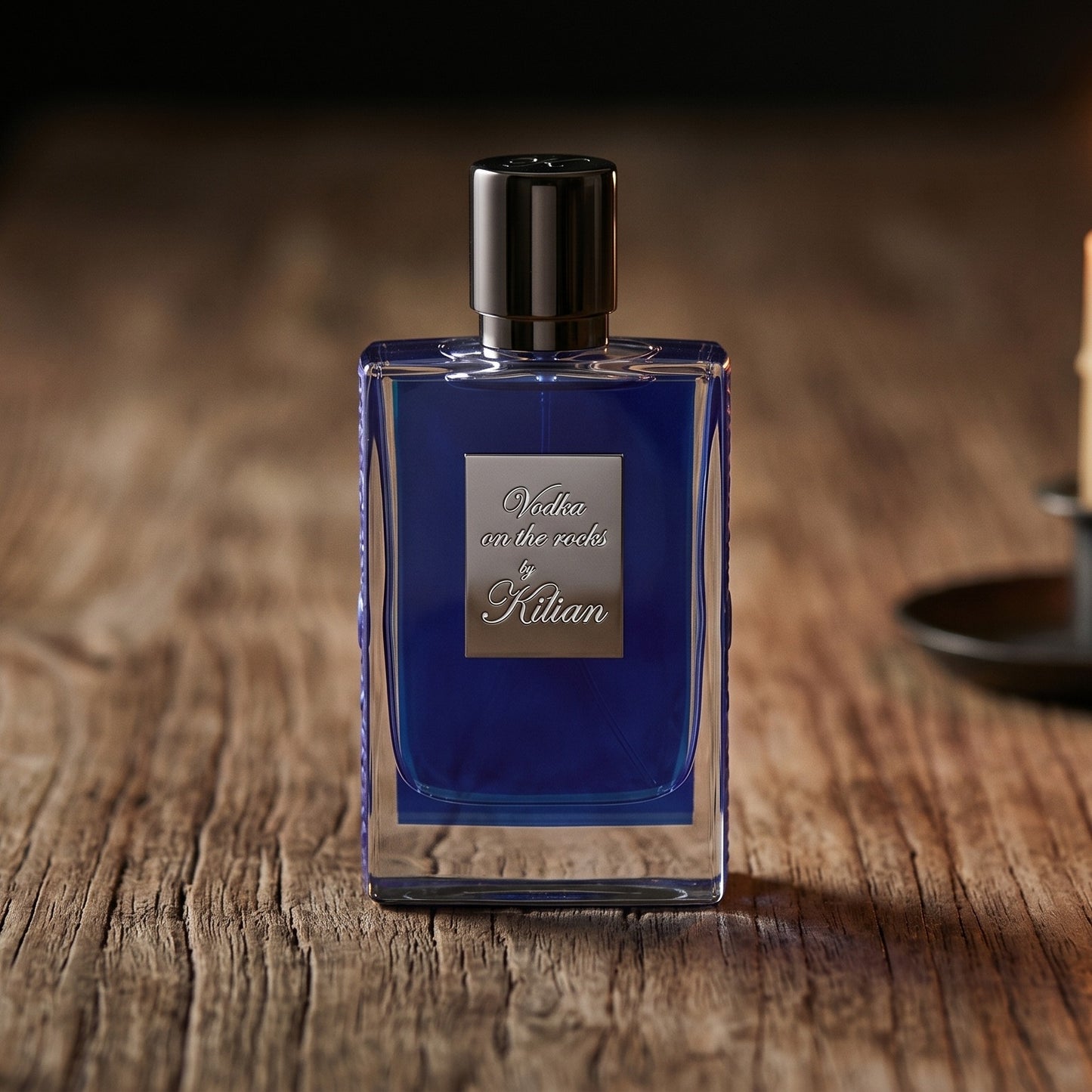 Kilian Vodka On The Rocks EDP on aged teak with a candle burning gently to frame-right
