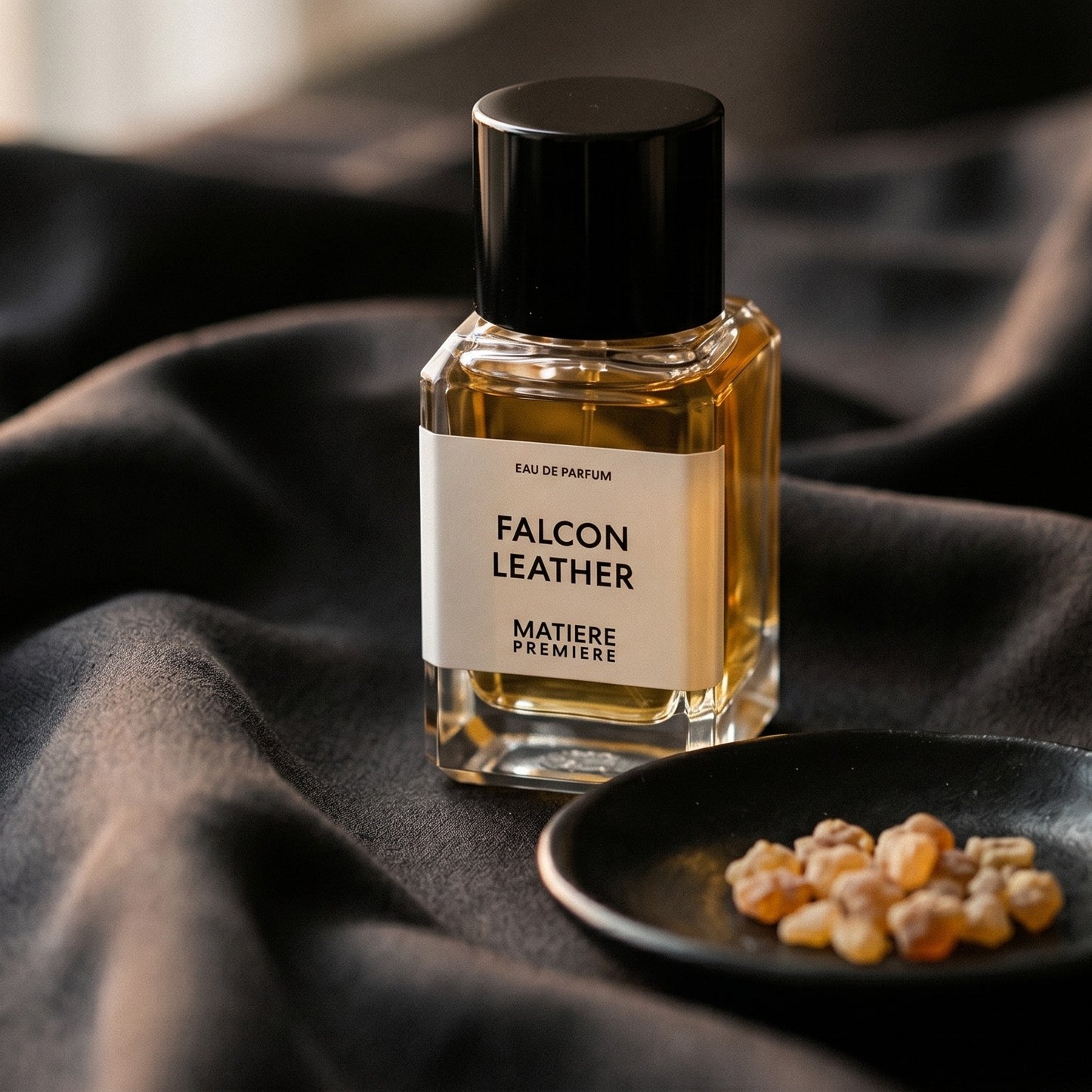 Matiere Premiere Falcon Leather EDP on charcoal silk with frankincense resin granules in a small saucer