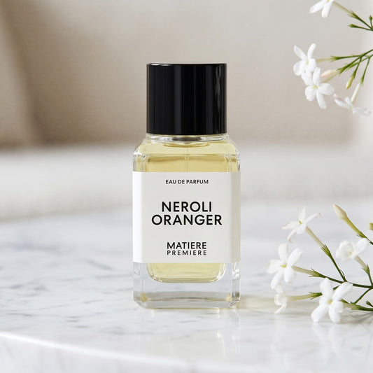 Matiere Premiere Neroli Oranger EDP on white carrara marble with jasmine sprigs placed to frame-right