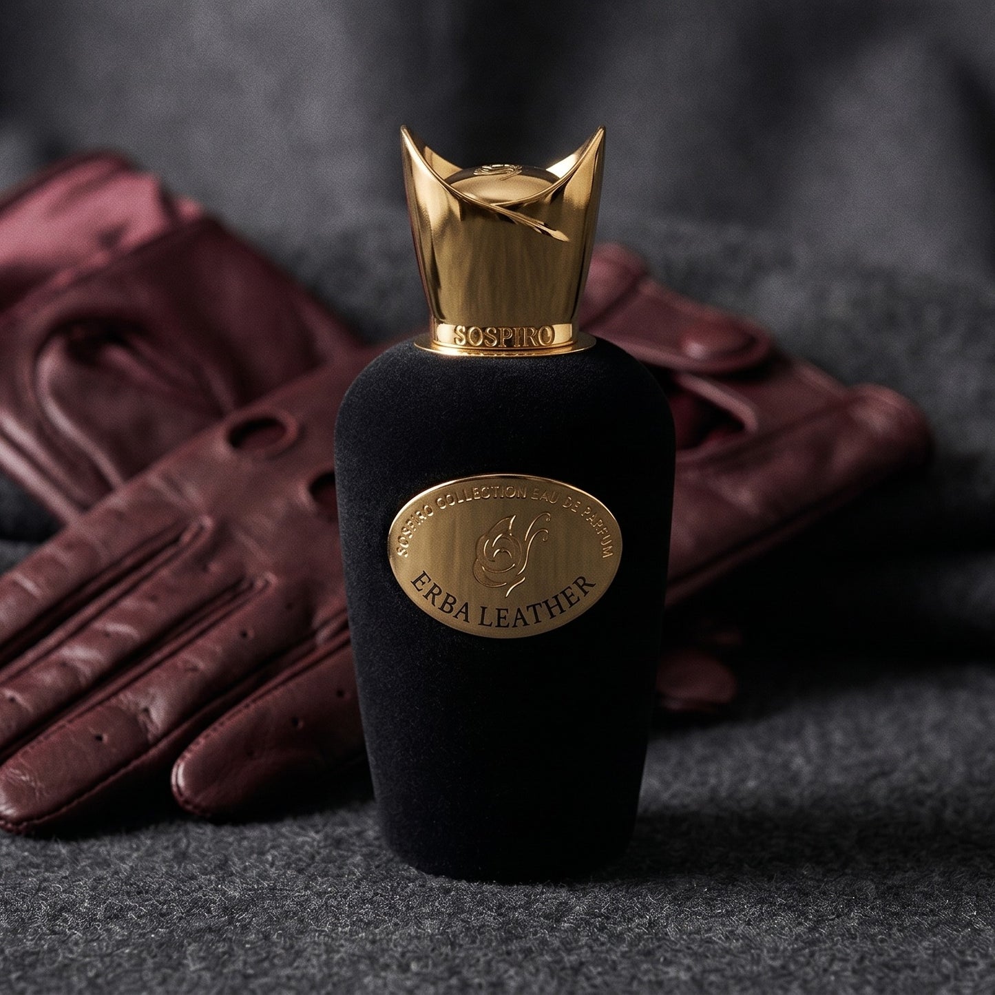 Sospiro Erba Leather EDP on charcoal felt with a silk-lined glove just behind the bottle
