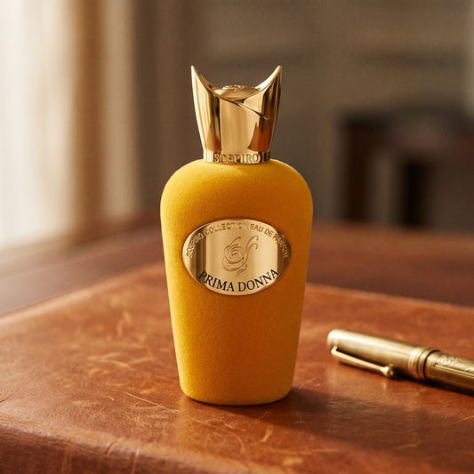 Sospiro Prima Donna EDP on aged cognac-leather surface with a brass fountain pen resting beside the bottle