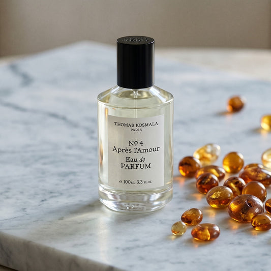 Thomas Kosmala Apres LAmour No 4 EDP on pale grey marble with amber resin beads scattered to one side