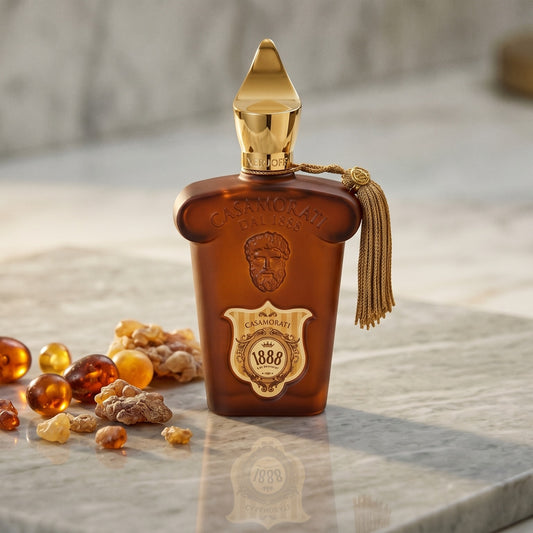 Xerjoff Casamorati 1888 EDP on pale grey marble with amber resin beads scattered to one side