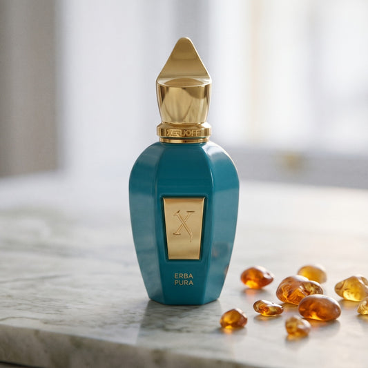 Xerjoff Erba Pura EDP on pale grey marble with amber resin beads scattered to one side