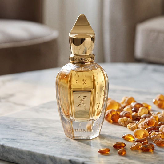 Xerjoff Starlight Parfum on pale grey marble with amber resin beads scattered to one side