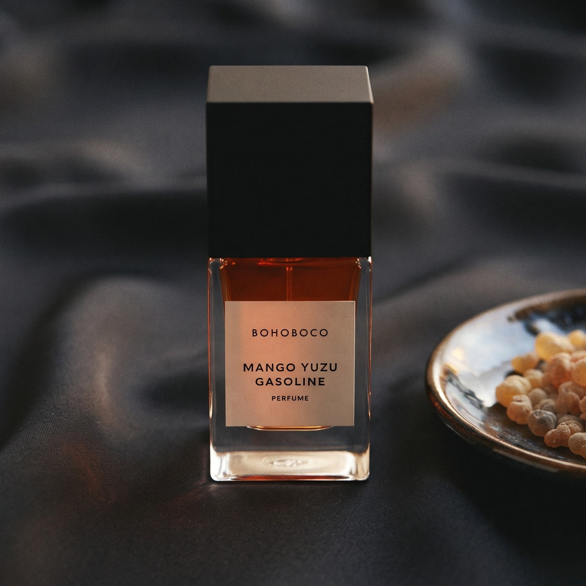Bohoboco Mango Yuzu Gasoline Perfume on charcoal silk with frankincense resin granules in a small saucer