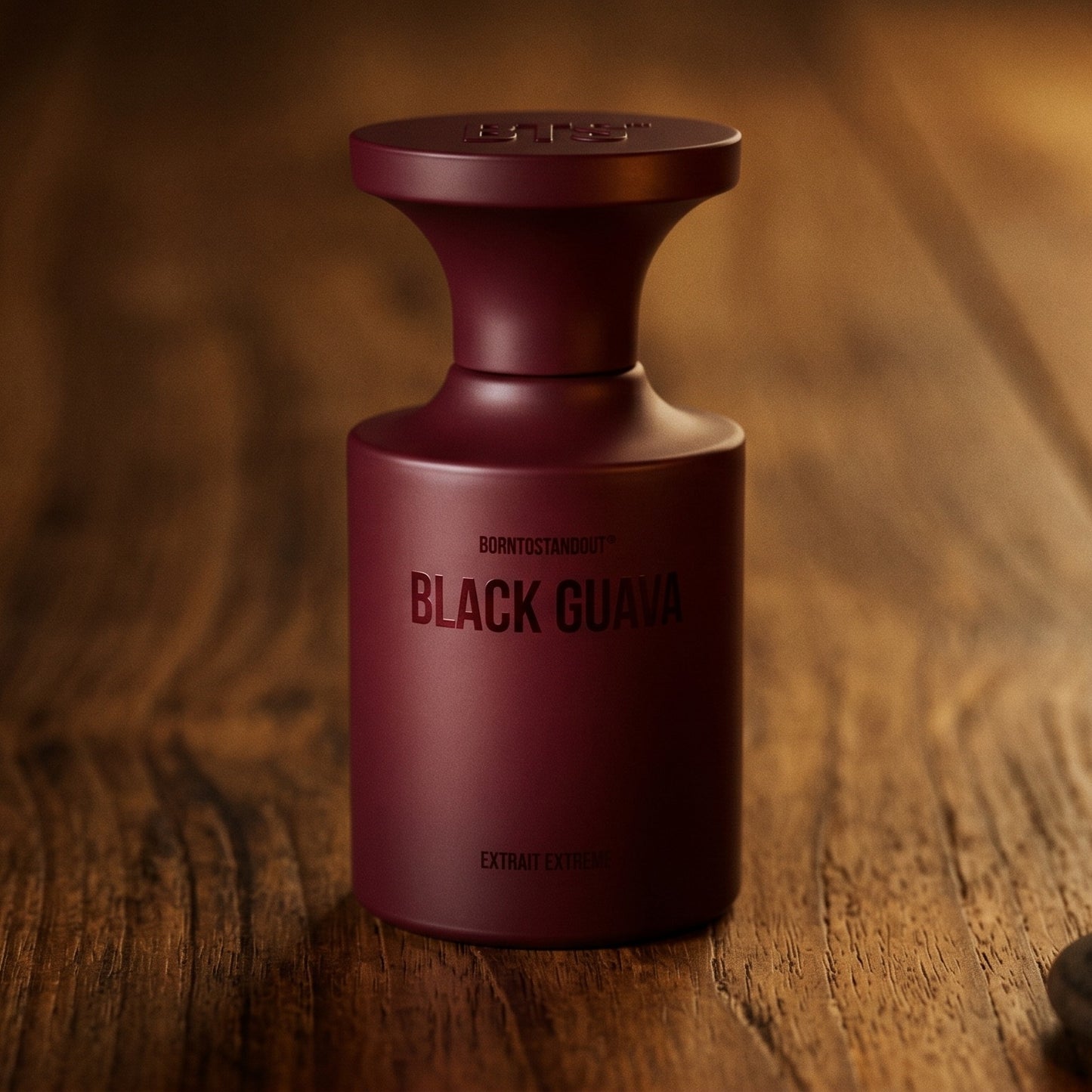 Borntostandout Black Guava Extrait Extreme on walnut side table with a pair of lit votives beside the bottle