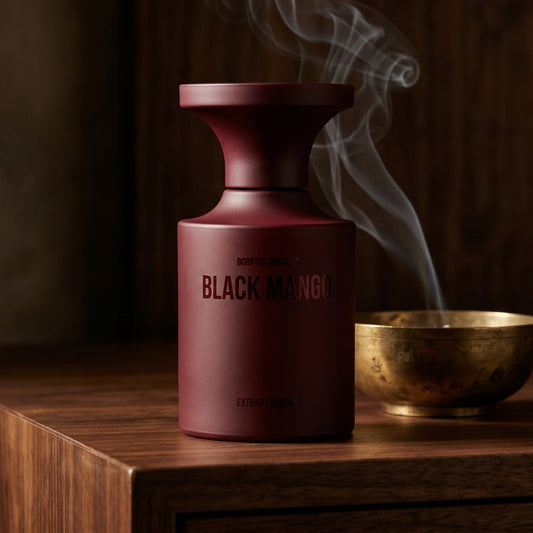 Borntostandout Black Mango Extrait Extreme on ebony surface with a hammered copper censer releasing frankincense haze