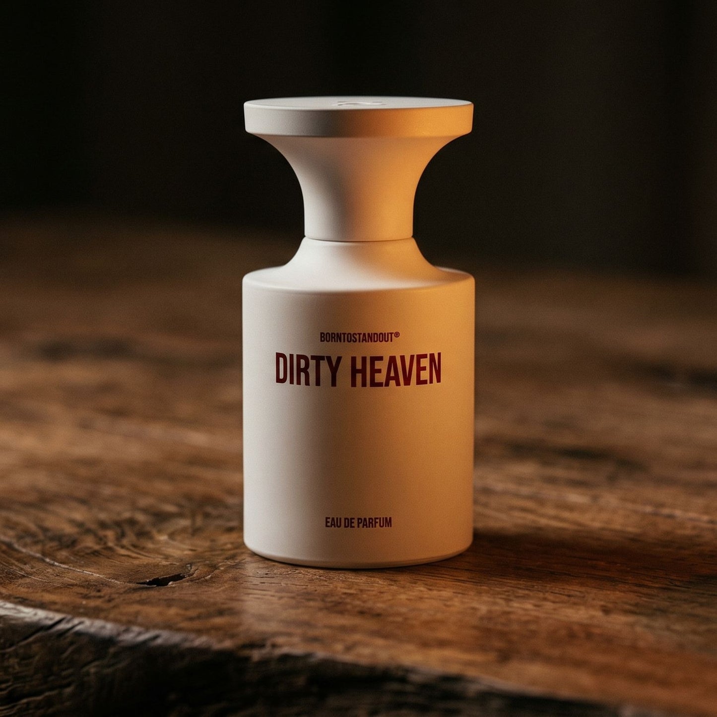 Borntostandout Dirty Heaven EDP on reclaimed oak surface with a glass hurricane lamp softly glowing
