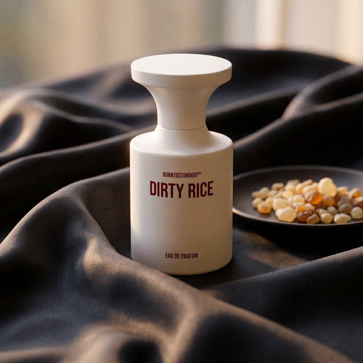 Borntostandout Dirty Rice EDP on burnt-orange silk with smoldering agarwood on a stone dish