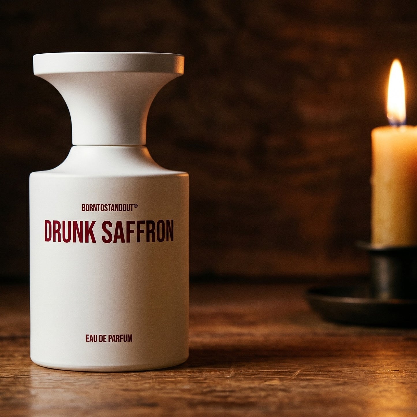 Borntostandout Drunk Saffron EDP on reclaimed oak surface with a glass hurricane lamp softly glowing