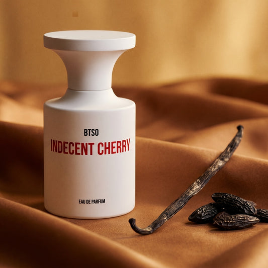 Borntostandout Indecent Cherry EDP on cream-colored silk with a split vanilla bean and cocoa nibs