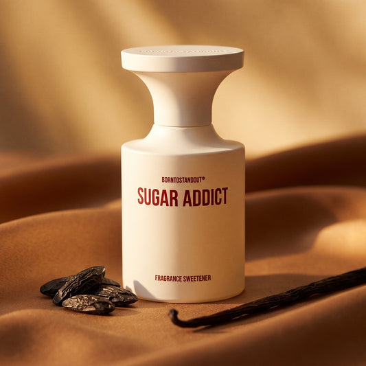 Borntostandout Sugar Addict EDP on warm caramel silk with a vanilla pod and tonka bean beside the bottle