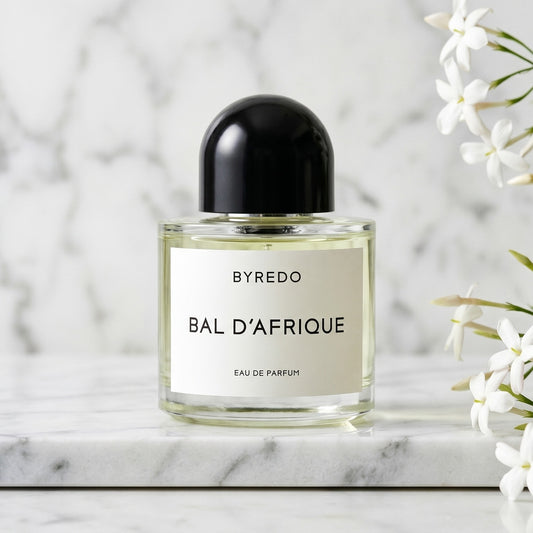 Byredo Bal'd Afrique on cream marble with a small bunch of gardenia blooms