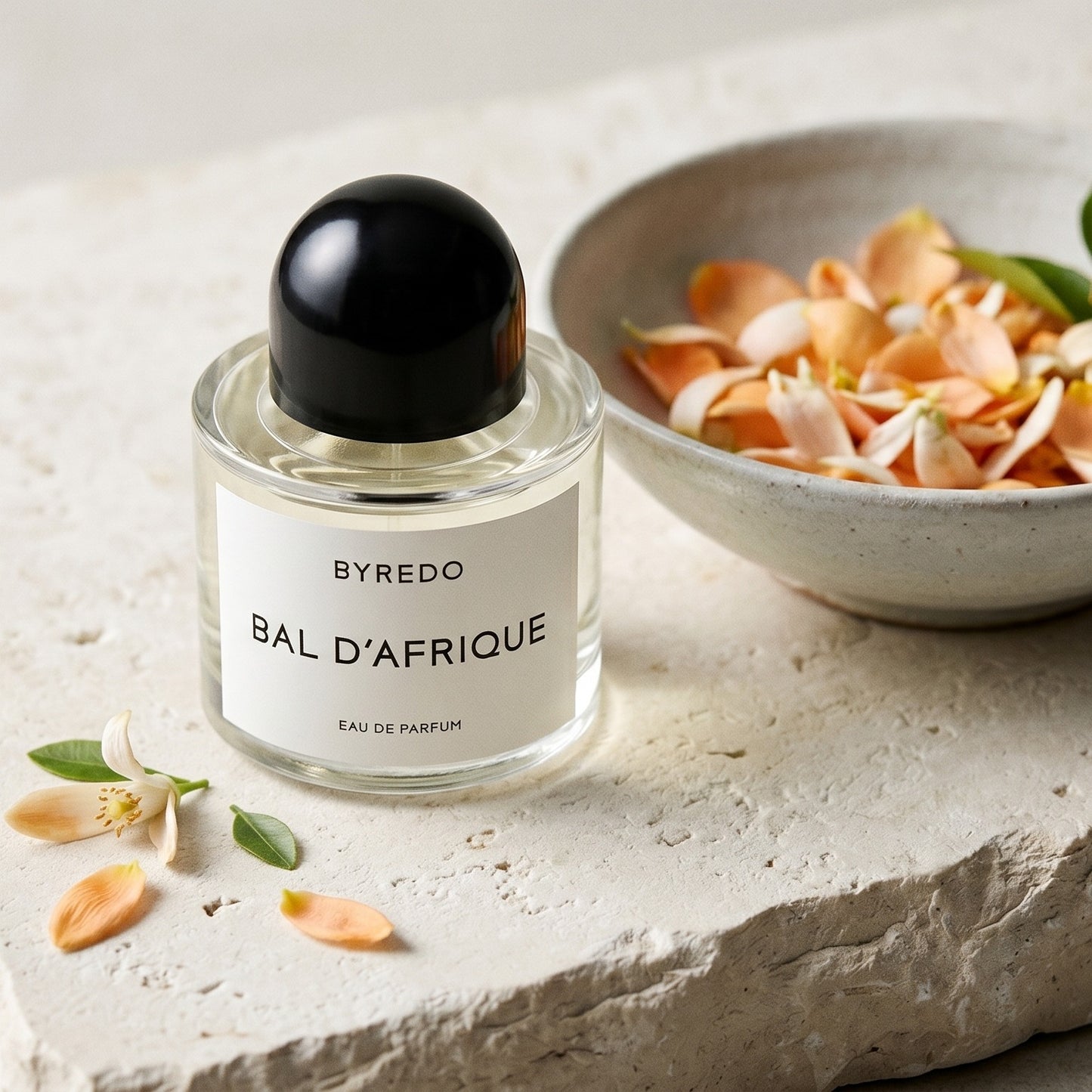 Byredo Bal'd Afrique on ivory stone with tuberose petals in a cut-glass saucer