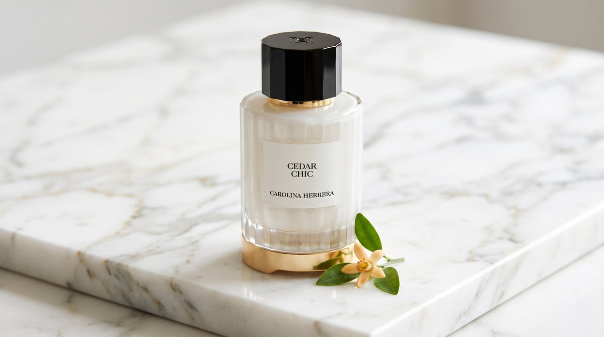 Carolina Herrera Cedar Chic EDP on white carrara marble with a sprig of orange blossom