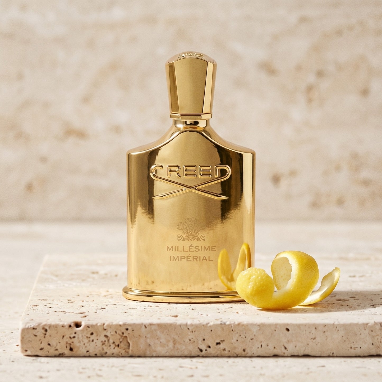 Creed Millesime Imperial on pale marble with a grapefruit rind curled into a spiral