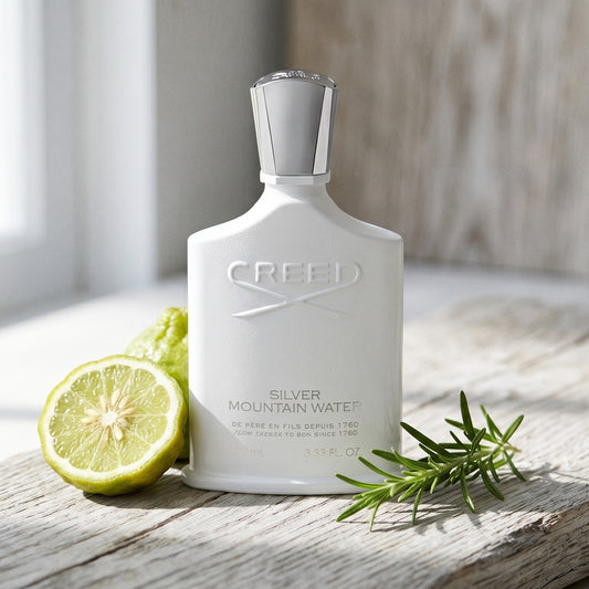 Creed Silver Mountain Water on bleached oak with a halved bergamot and sprig of rosemary