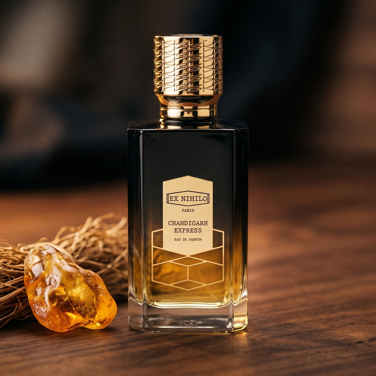 Ex Nihilo Chandigarh Express EDP on dark walnut with cut vetiver roots beside a piece of amber benzoin resin