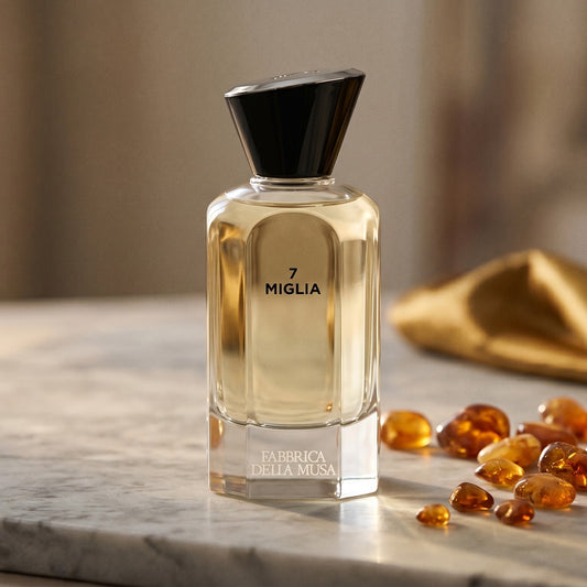 Fabbrica Della Musa 7 Migila EDP on pale grey marble with amber resin beads scattered to one side