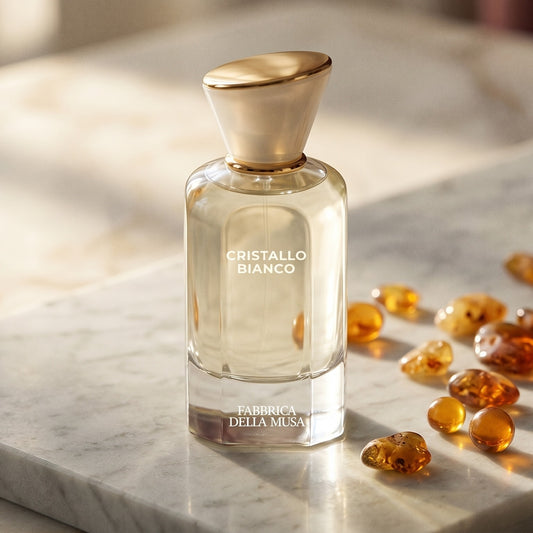 Fabbrica Della Musa Cristallo Bianco EDP on pale grey marble with amber resin beads scattered to one side