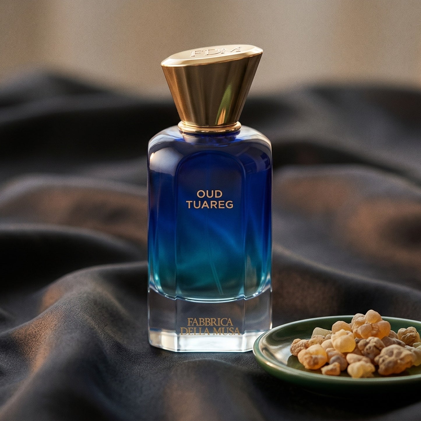 Fabbrica Della Musa Oud Tuareg Extrait de Parfum on charcoal raw silk with amber resin pieces near the bottle base