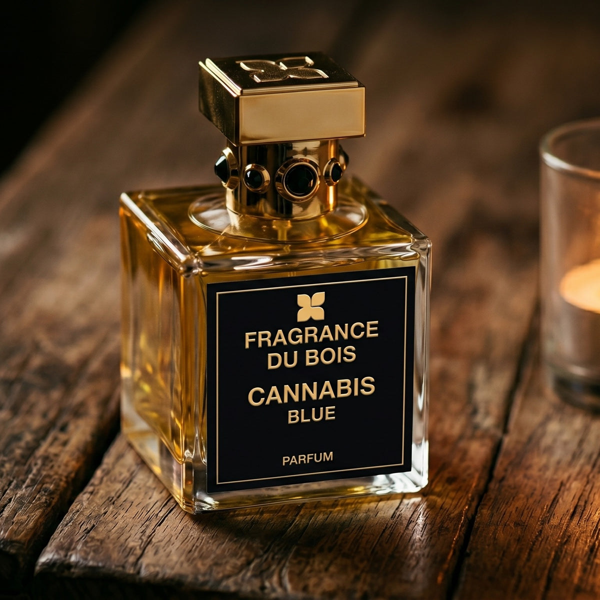 Fragrance Du Bois Cannibis Blue on rosewood surface with a squat brass candle flickering nearby