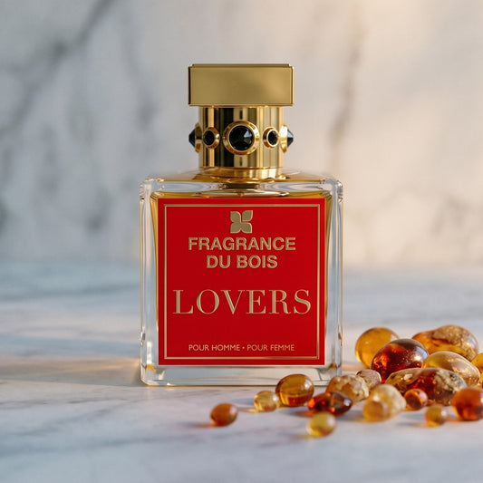 Fragrance Du Bois Lovers on pale grey marble with amber resin beads scattered to one side