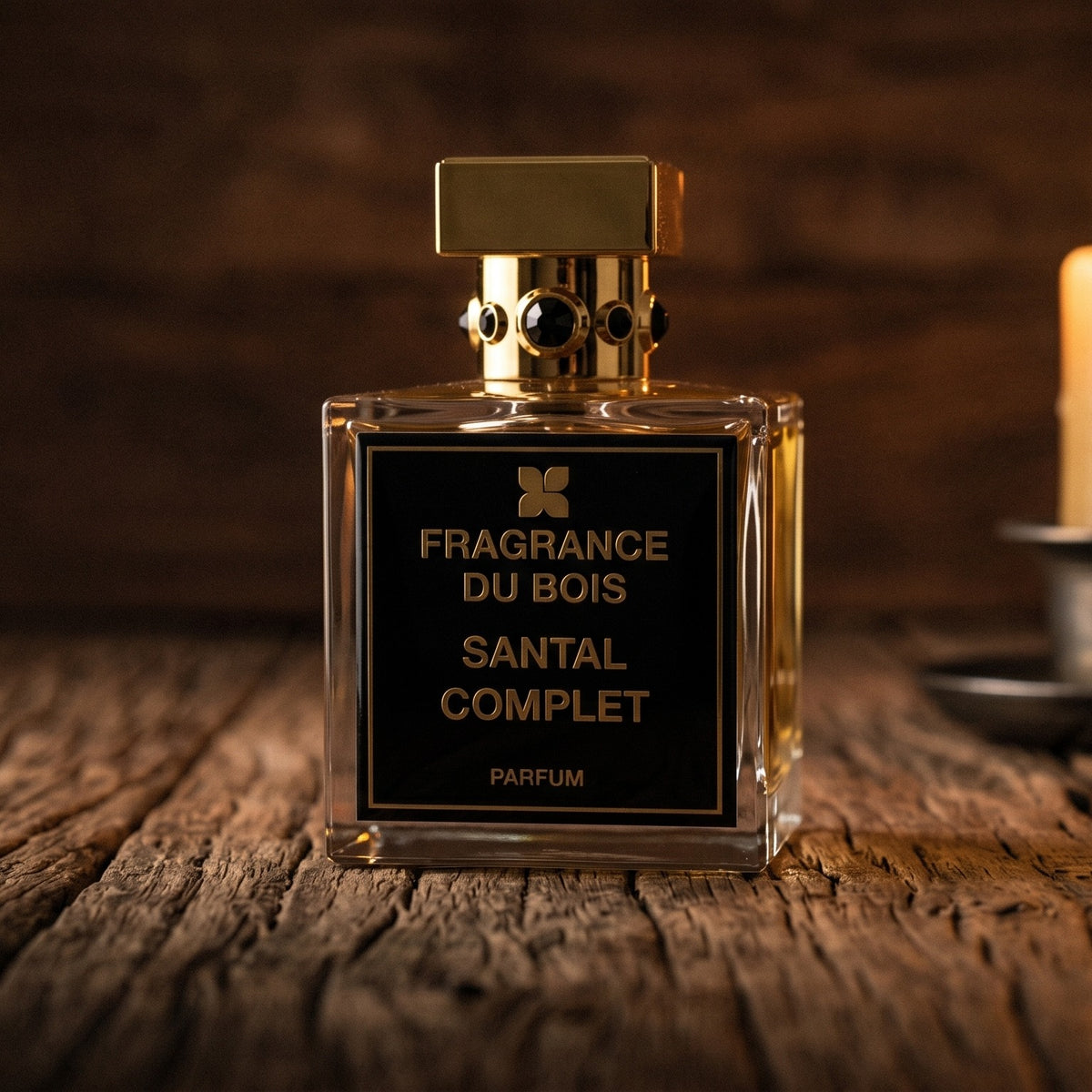 Fragrance Du Bois Santal Complet Parfum on reclaimed oak surface with a glass hurricane lamp softly glowing