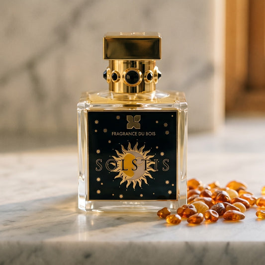 Fragrance Du Bois Solstis on cream stone with a scatter of honey-colored ambergris flakes