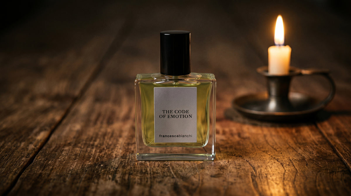 Francesca Bianchi The Code Emotion Extrait de Parfume on aged teak with a candle burning gently to frame-right