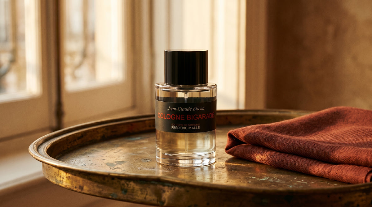 Frederic Malle Cologne Bigarade EDC on aged brass tray with a folded pashmina in rust tone