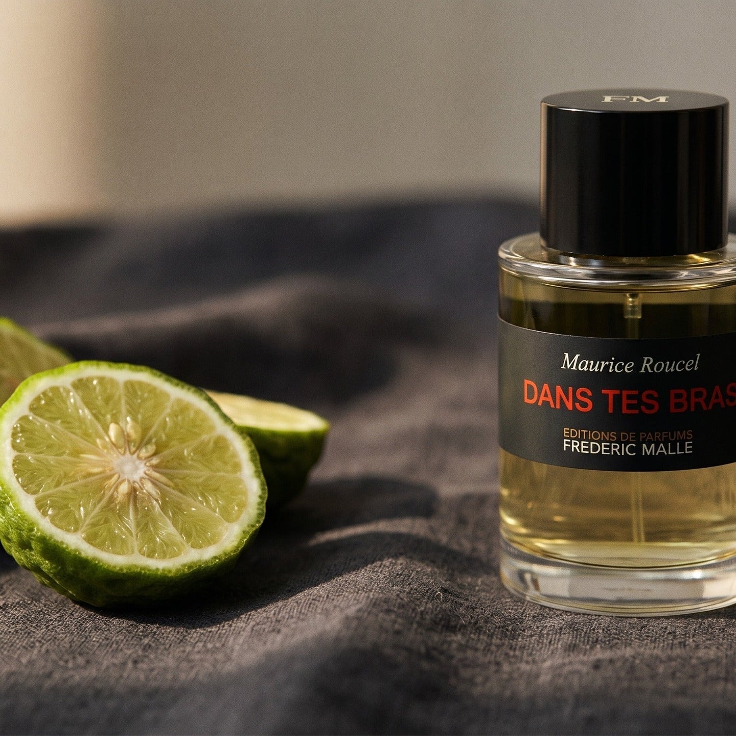 Frederic Malle Dans Tes Bras EDP on charcoal linen with a halved bergamot