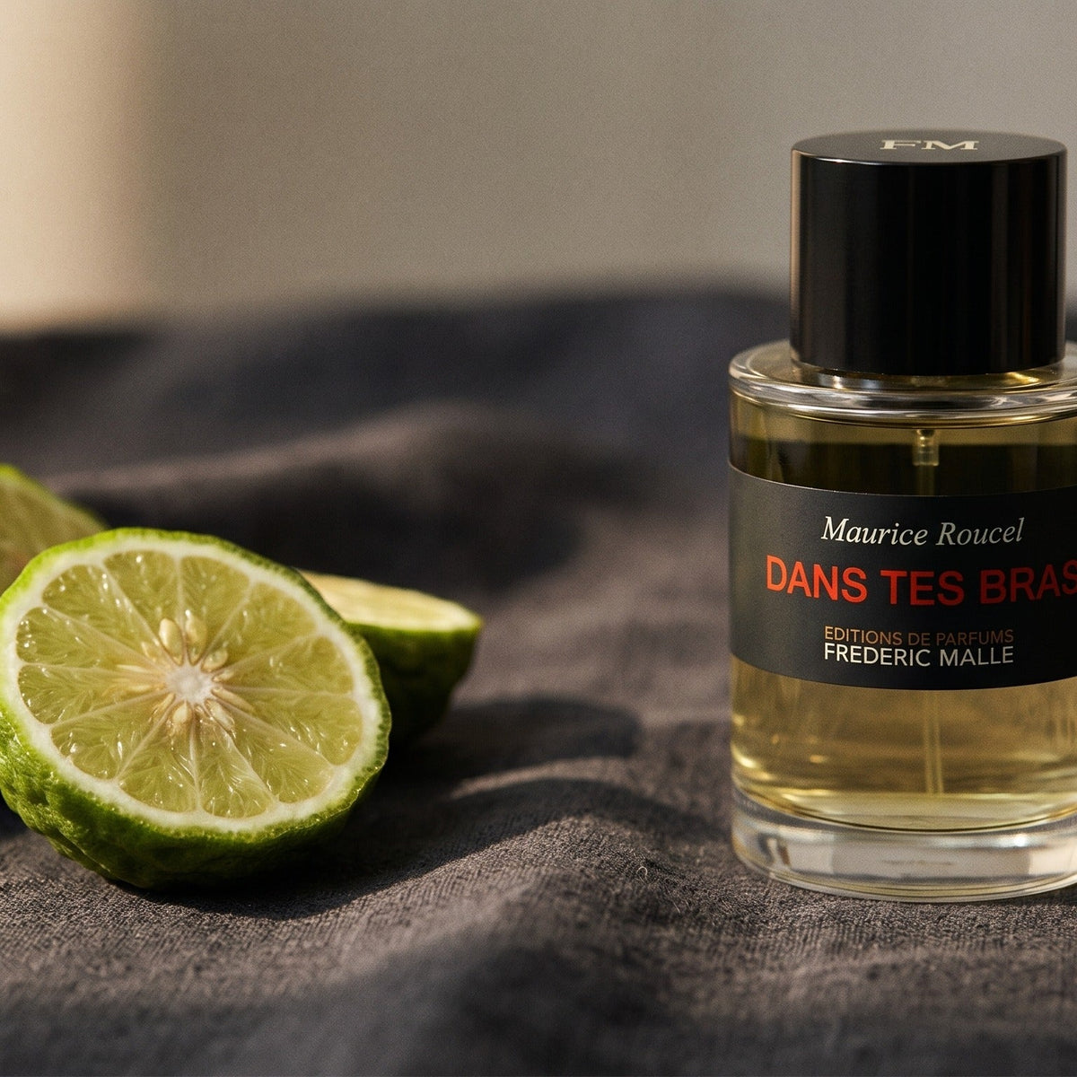 Frederic Malle Dans Tes Bras EDP on charcoal linen with a halved bergamot