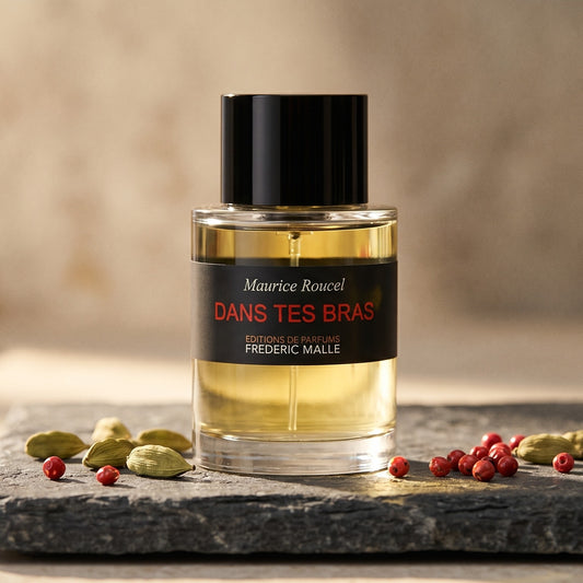 Frederic Malle Dans Tes Bras EDP on slate surface with a handful of dried chili threads near the bottle