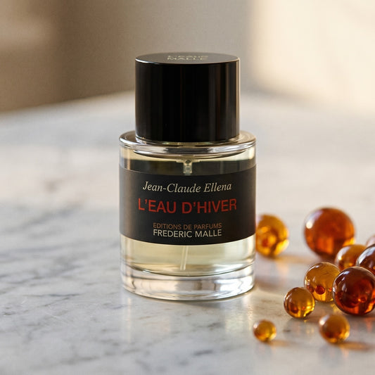 Frederic Malle L'Eau D'Hiver EDT on pale grey marble with amber resin beads scattered to one side
