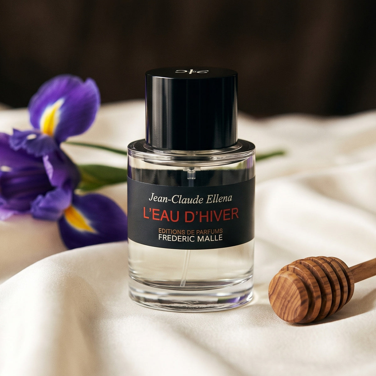 Frederic Malle L'Eau D'Hiver EDT on cream silk with a wooden honey dipper beside a single iris flower
