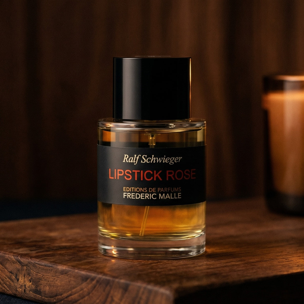 Frederic Malle Lipstick Rose EDP on walnut side table with a pair of lit votives beside the bottle