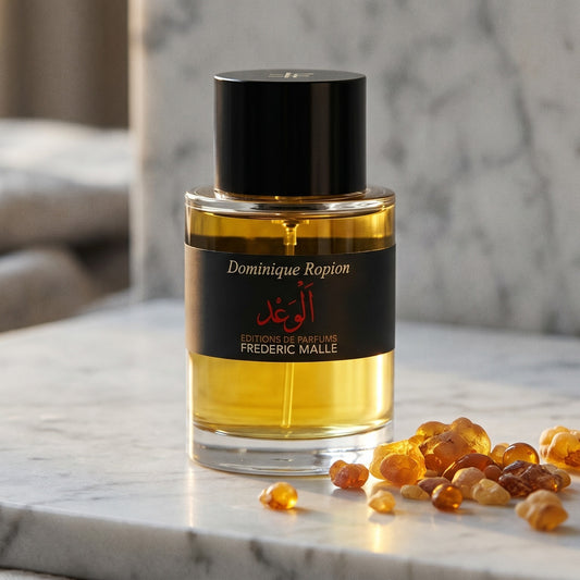 Frederic Malle Promise Eau de Parfum on warm ivory travertine with labdanum chunks clustered by the base