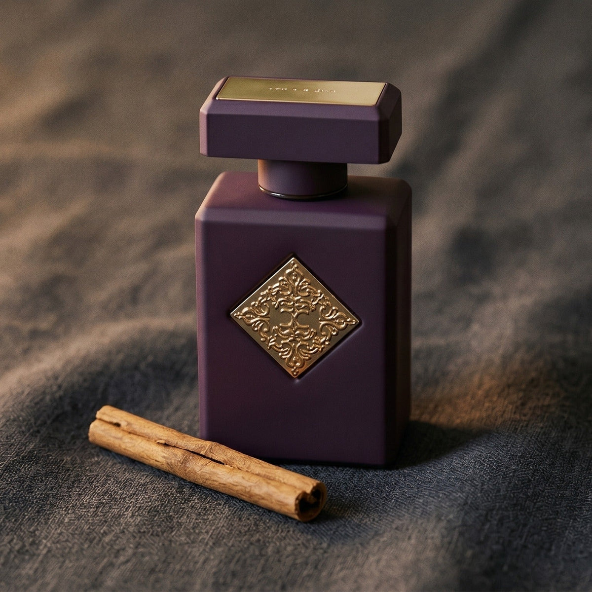 Initio Side Effect EDP on charcoal linen with a cinnamon stick