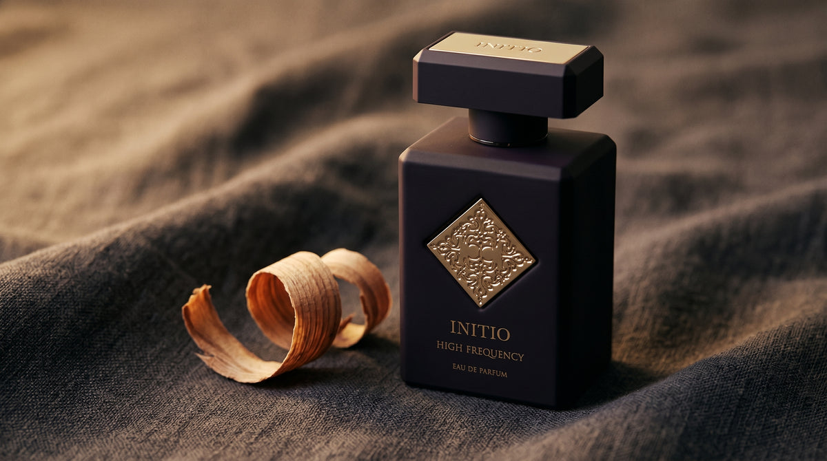 Initio High Frequency EDP on charcoal linen with a curl of cedarwood shaving beside the bottle