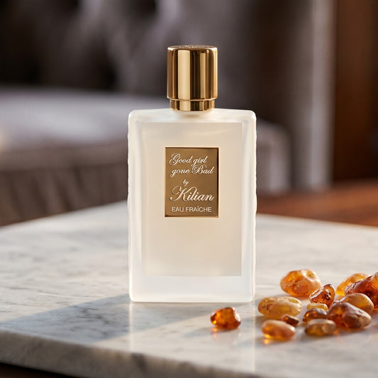 Kilian Good Girl Gone Bad EDP on cream stone with a scatter of honey-colored ambergris flakes