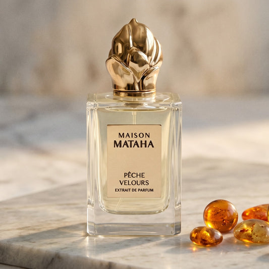 Maison Mataha Peche Velours on cream stone with a scatter of honey-colored ambergris flakes