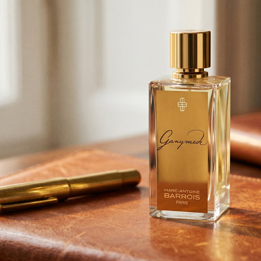 Marc-Antoine Barrois Ganymede EDP on aged cognac-leather surface with a brass fountain pen resting beside it