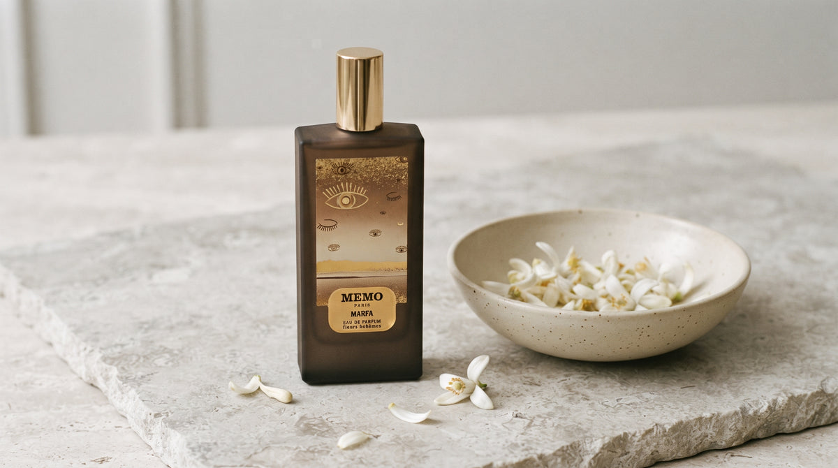 Memo Paris Marfa EDP on pale stone with orange-blossom petals in a shallow bowl
